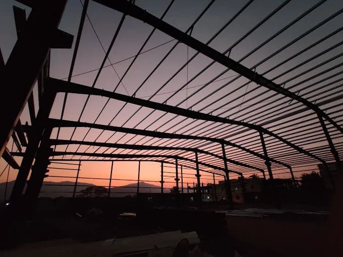 Steel roof frame silhouetted at sunset during erection