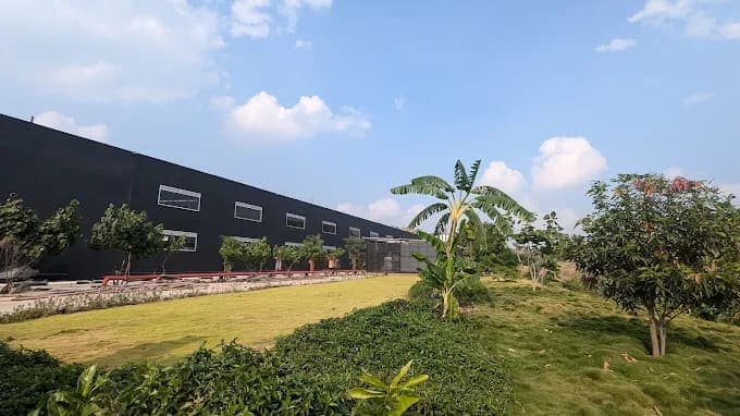 Manufacturing unit with dark cladding beside landscaped grounds